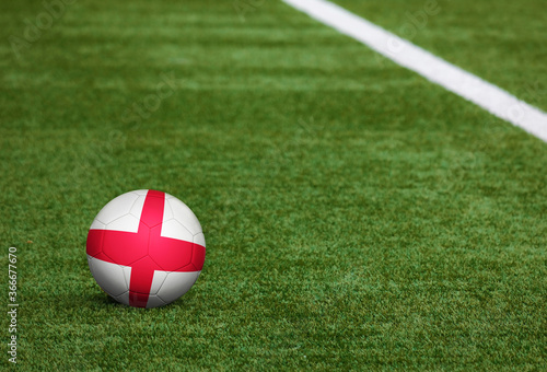 England flag on ball at soccer field background. National football theme on green grass. Sports competition concept.