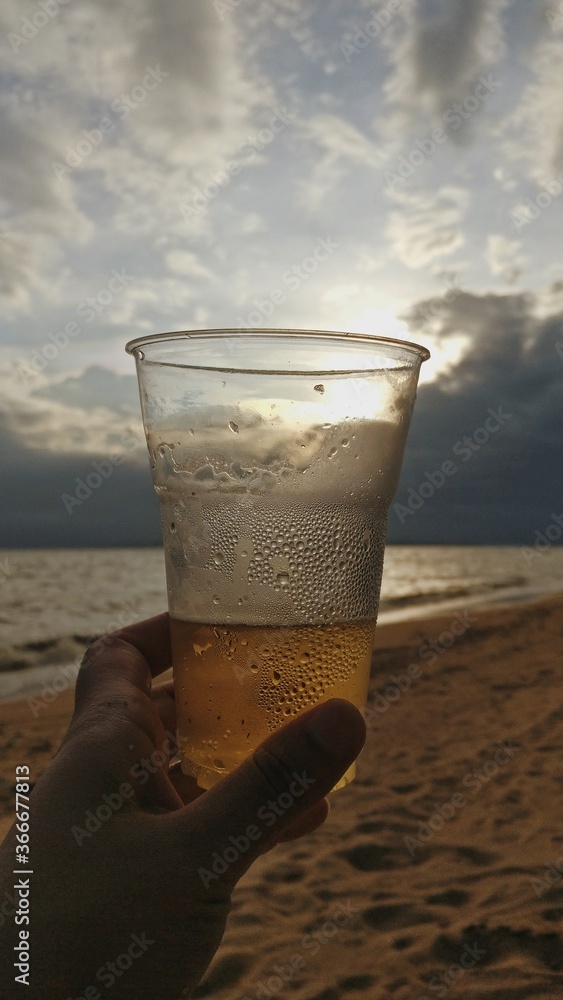 Vaso de cerveza al atardecer en la playa Stock Photo | Adobe Stock