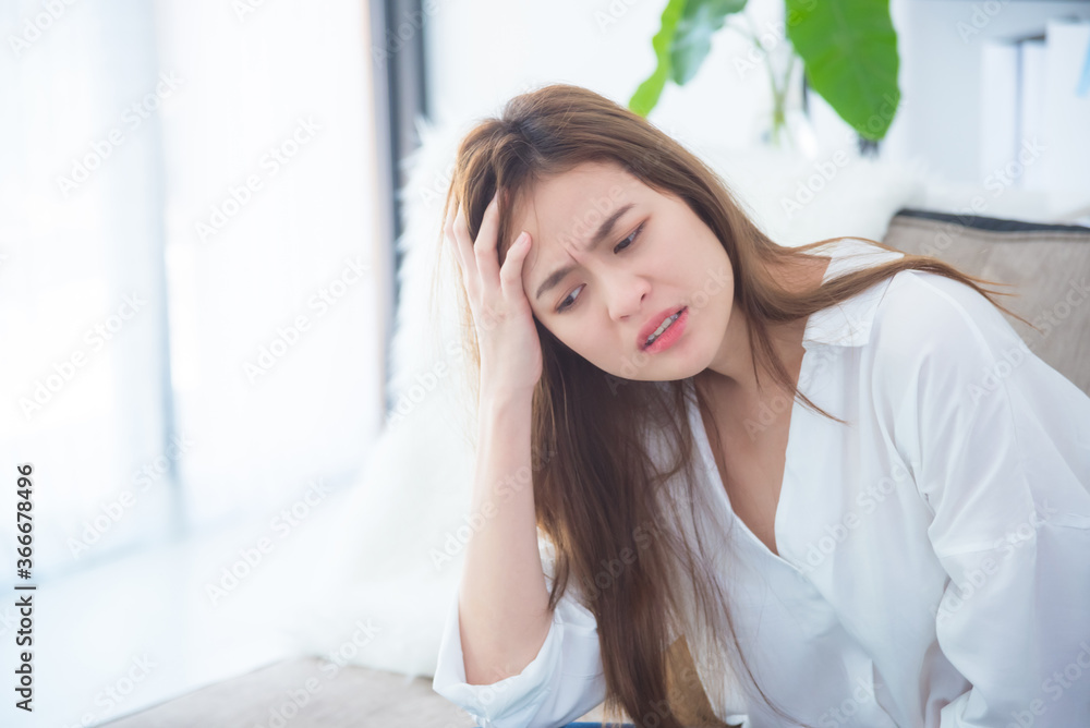 Beautiful asian woman sitting in living room with unhappy face .Woman having headache from migraine. Beautiful asian woman sitting in living room with unhappy face .Woman having headache from migraine.