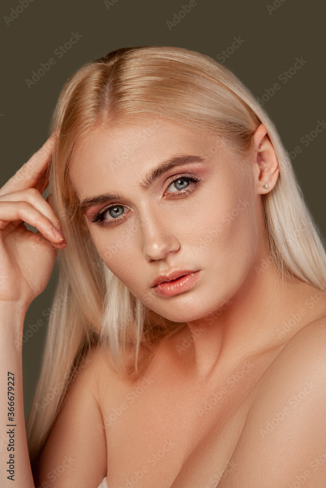 Fototapeta premium Beauty portrait. Skin rejuvenation. Blonde woman with natural makeup bare shoulders isolated on brown.