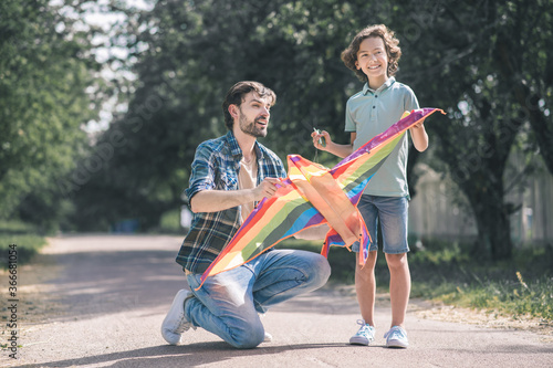 Dark-haired man holding a kite, his son looking excited