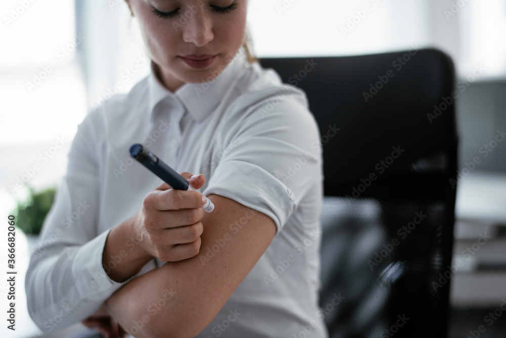 Businesswoman giving herself an injection of insulin. Businesswoman giving herself an injection of insulin.