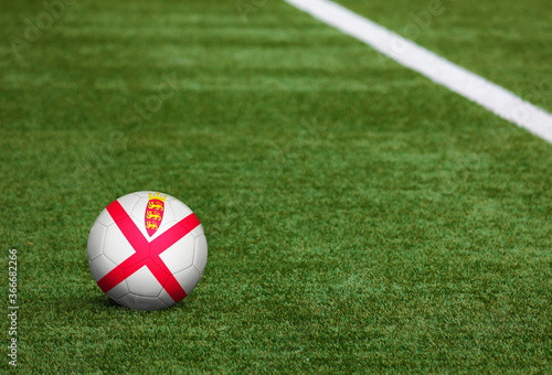 Jersey flag on ball at soccer field background. National football theme on green grass. Sports competition concept.