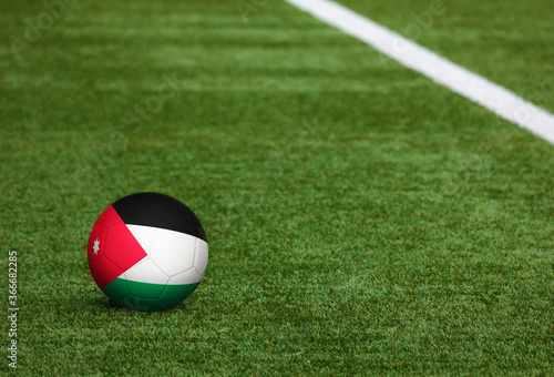 Jordan flag on ball at soccer field background. National football theme on green grass. Sports competition concept.