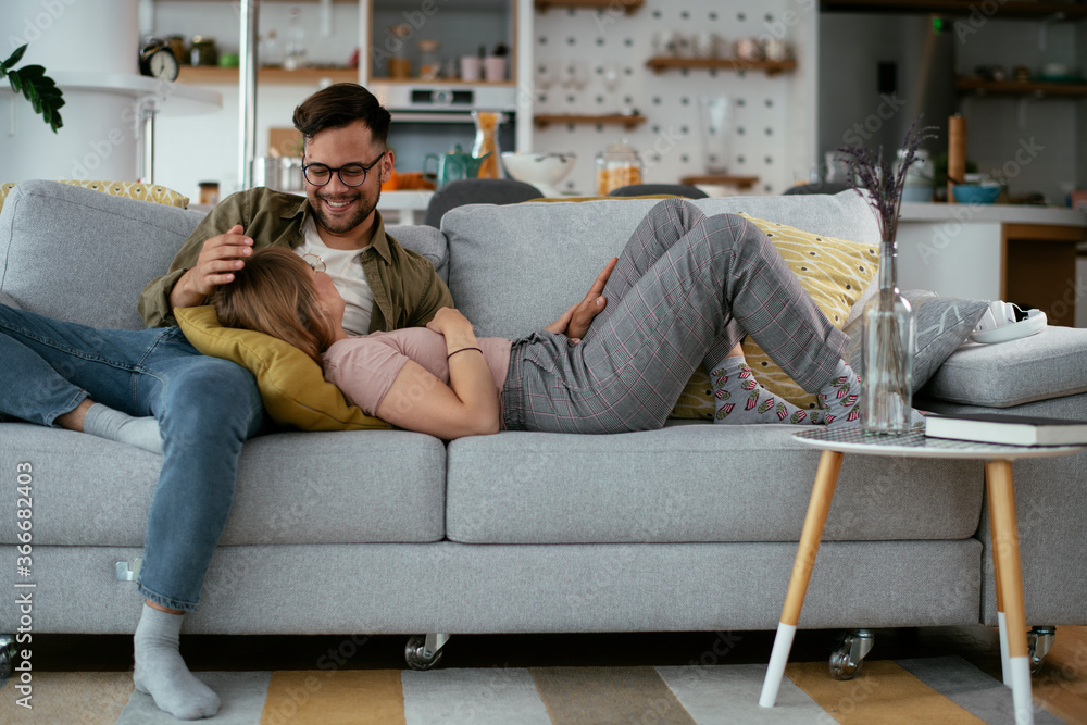 Fototapeta premium Husband and wife enjoying on sofa. Happy couple relaxing in living room. 