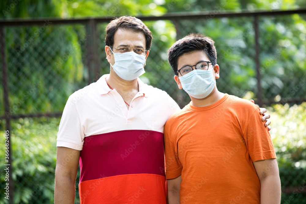 Father and son with protective face mask looking at camera Father and son with protective face mask looking at camera