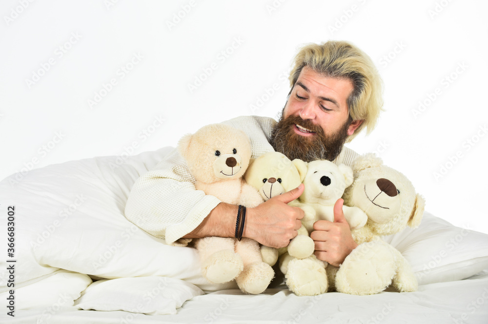feeling happy and childlike. Psychological problems with imaginary friends. good morning. excited mature man with toys in bed. feel childish. bearded man hipster play with bear. toys for adult