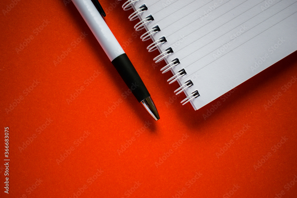 Cut out notepad and pen on orange background Cut out notepad and pen on orange background