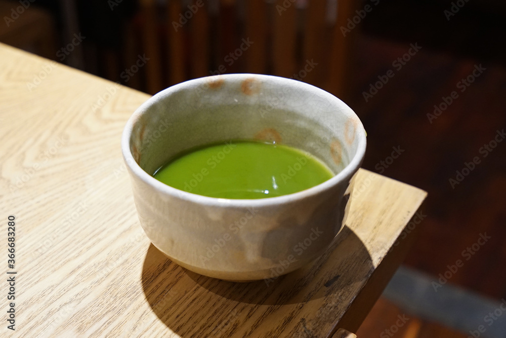 Close up ceramic cup of hot Matcha green tea on wooden table Close up ceramic cup of hot Matcha green tea on wooden table