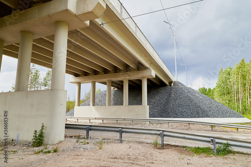 Фотография Bottom view of the prestressed concrete beams and piers of bridge crossing many-lane expressway of road