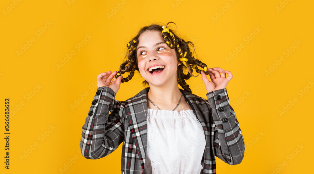 curls well. little happy girl with curlers in hair. fabric mask under eyes for beauty. cute kid standing with patches under eyes. Child fashion model concept. Child making hairstyle