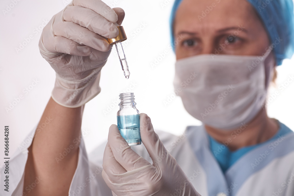 Researchers hand mixing solution from pipette in bottle at lab Researchers hand mixing solution from pipette in bottle at lab