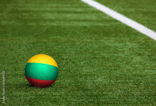 Lithuania flag on ball at soccer field background. National football theme on green grass. Sports competition concept.