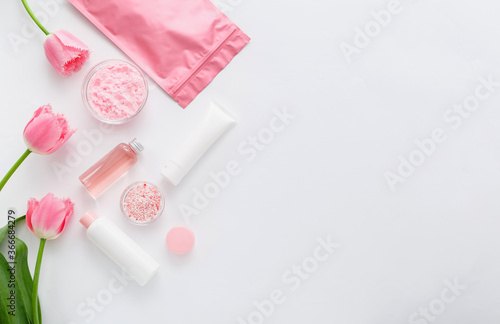 Beauty spa medical skincare bath pink products. Cosmetic bottles, tubes, cream packaging, powder and beads for bathtubs with rose. Cosmetics SPA branding mock up for bath products. Flat lay copy space