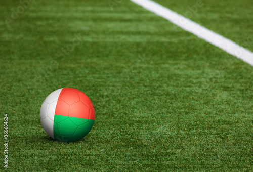 Madagascar flag on ball at soccer field background. National football theme on green grass. Sports competition concept.
