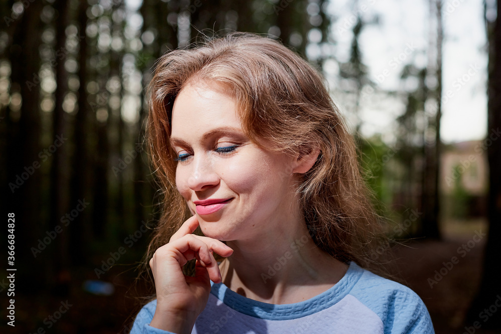 Portrait of cute blonde girl walking in forest outdoors. Nice woman posing on nature landscape with with pine trees. Portrait of cute blonde girl walking in forest outdoors. Nice woman posing on nature landscape with with pine trees.