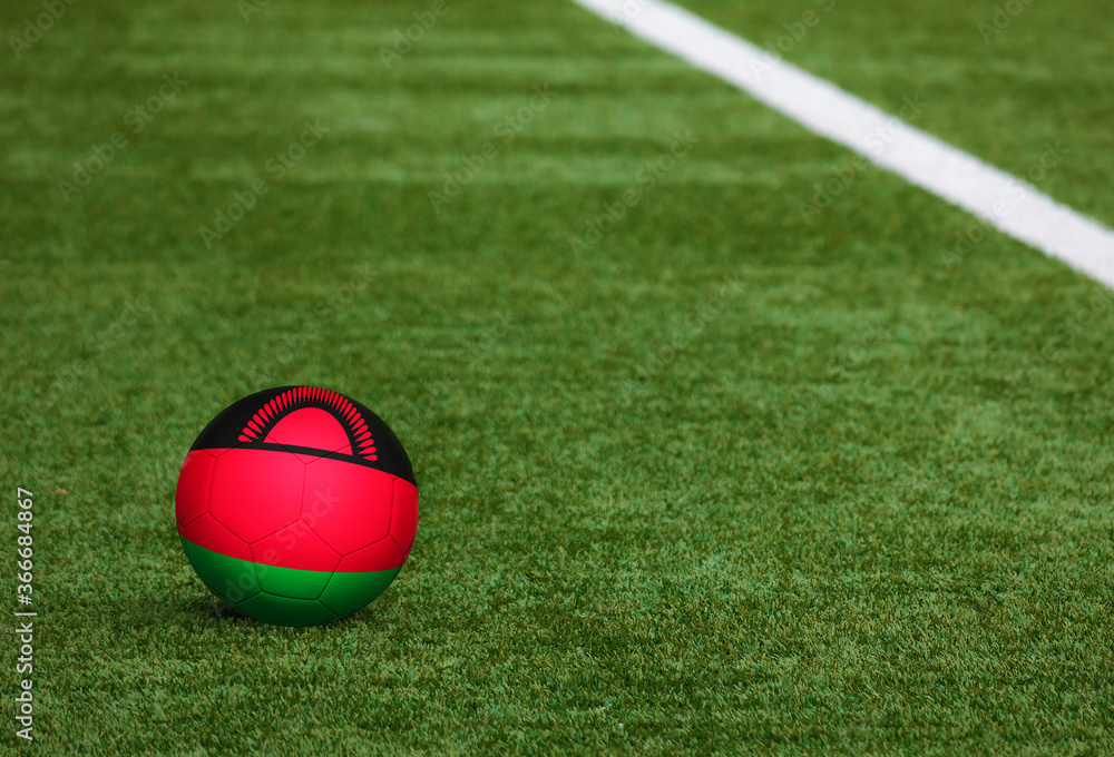 Malawi flag on ball at soccer field background. National football theme on green grass. Sports competition concept. Malawi flag on ball at soccer field background. National football theme on green grass. Sports competition concept.