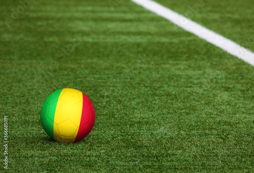 Mali flag on ball at soccer field background. National football theme on green grass. Sports competition concept.
