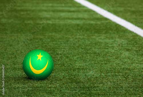 Mauritania flag on ball at soccer field background. National football theme on green grass. Sports competition concept.
