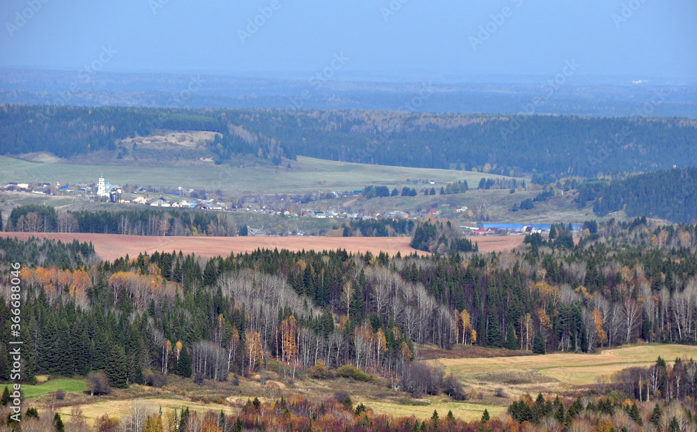 The expanses of the Western Urals. Panorama of autumn forests and fields overlooking the village of Bym from the top of the White Mountain.