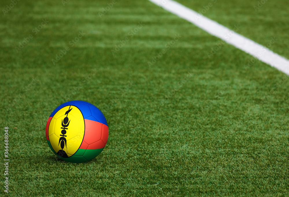 Naklejka Flaga Nowej Kaledonii na piłkę w tle boisko do piłki nożnej. Narodowy motyw piłki nożnej na zielonej trawie. Koncepcja zawodów sportowych.