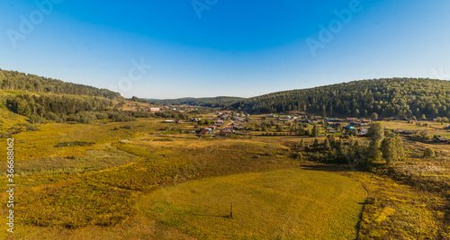 Summer rural landscape with hills  forest  sky and the village