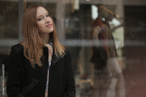 The girl in black coat. Beautiful emotional young girl in the city. Shawl or handkerchief on a person. 