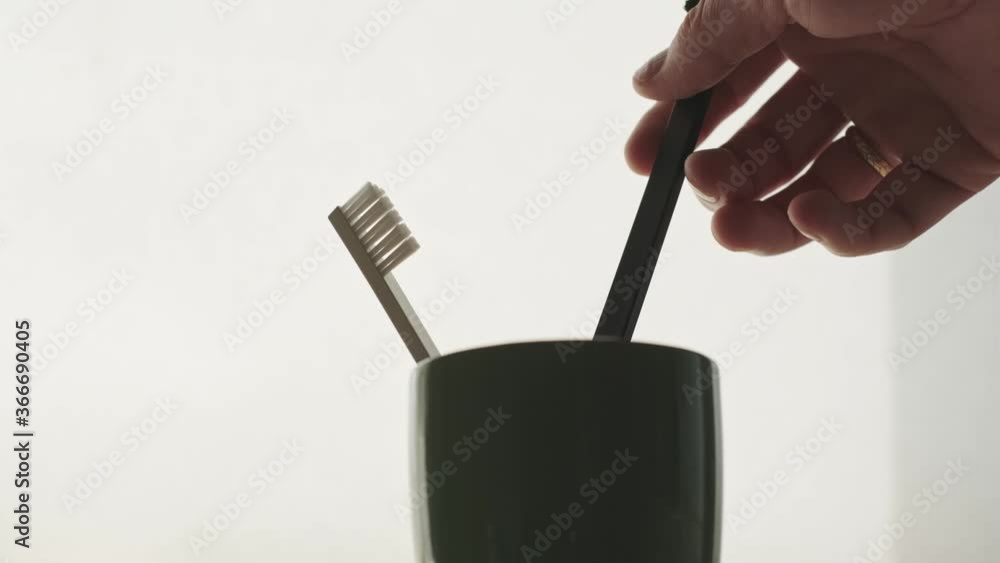 A man's hand takes a toothbrush from a mug/ A man's hand takes a toothbrush from a mug/