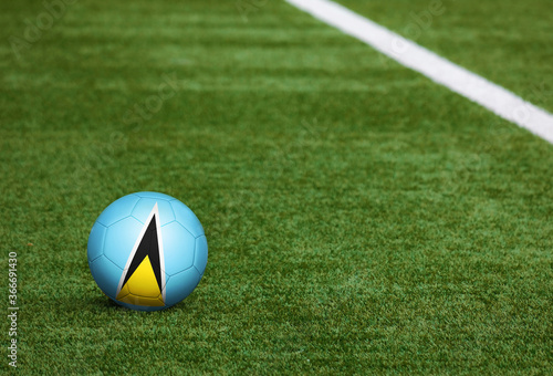Saint Lucia flag on ball at soccer field background. National football theme on green grass. Sports competition concept.