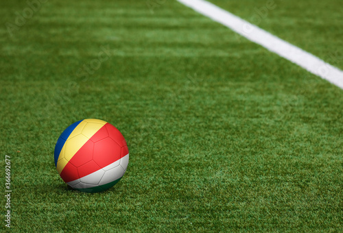 Seychelles flag on ball at soccer field background. National football theme on green grass. Sports competition concept.