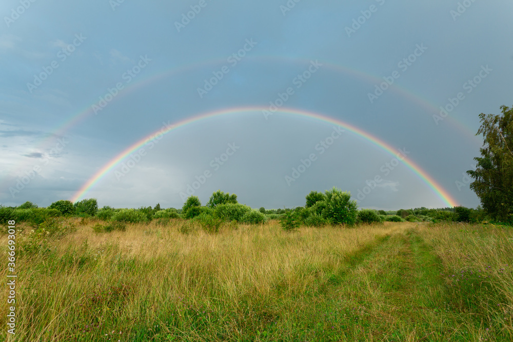 Summer field with double rainbow after the rain. Horizontal image. Summer field with double rainbow after the rain. Horizontal image.