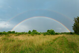 Summer field with double rainbow after the rain. Horizontal image.