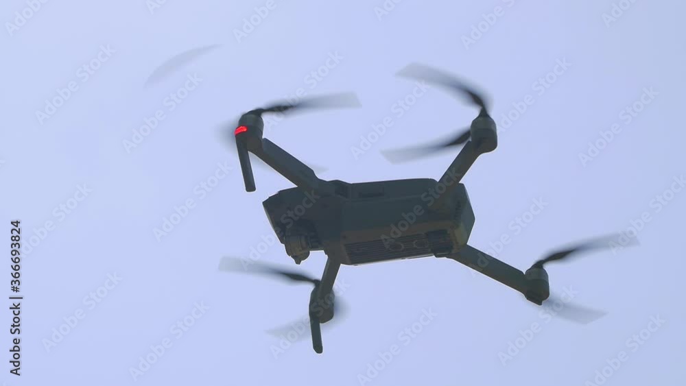 Drone in the sky closeup gray hovers slow motion Drone in the sky closeup gray hovers slow motion