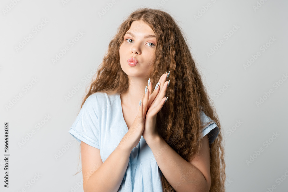 Naklejka premium Photo of thoughtful European young woman with curly long hair looks with dreamy expression aside. Isolated over white background.