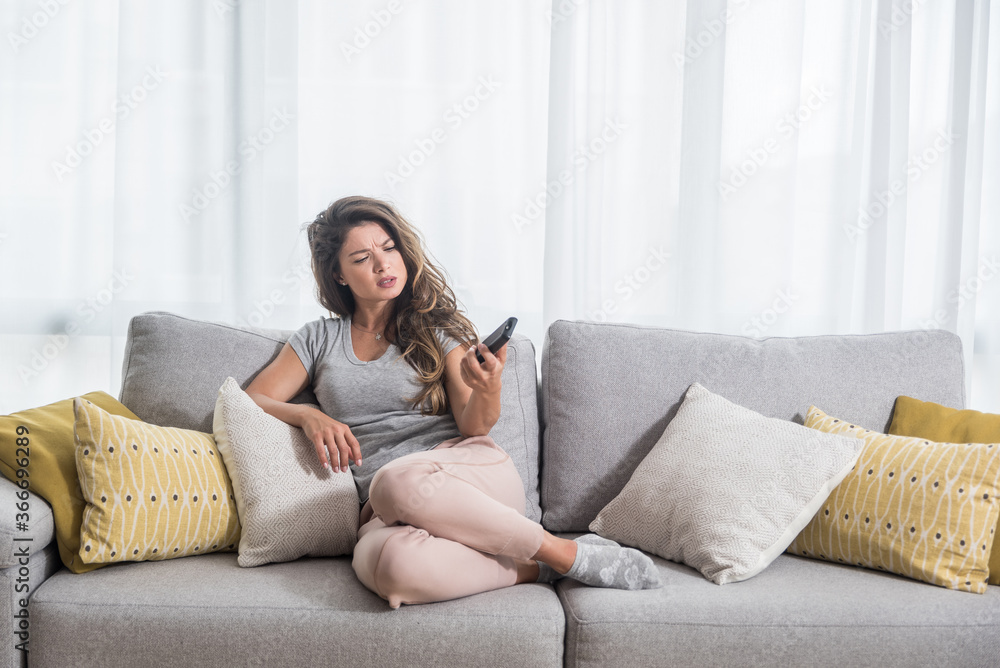 Young beautiful girl having trouble with batteries of the tv or television remote control cant change the program and watch the movie Young beautiful girl having trouble with batteries of the tv or television remote control cant change the program and watch the movie