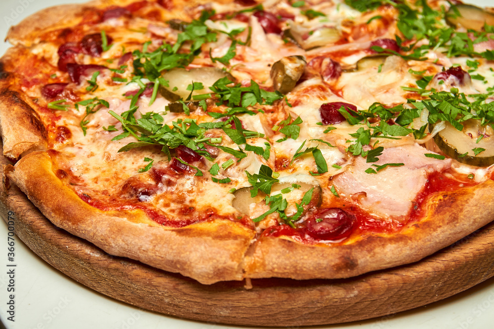Fresh pizza with bacon, tomatoes, pickles and cheese on a light background. Close-up, selective focus Fresh pizza with bacon, tomatoes, pickles and cheese on a light background. Close-up, selective focus