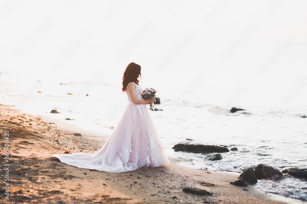 Romantic beautiful bride in white dress posing on the background sea Romantic beautiful bride in white dress posing on the background sea