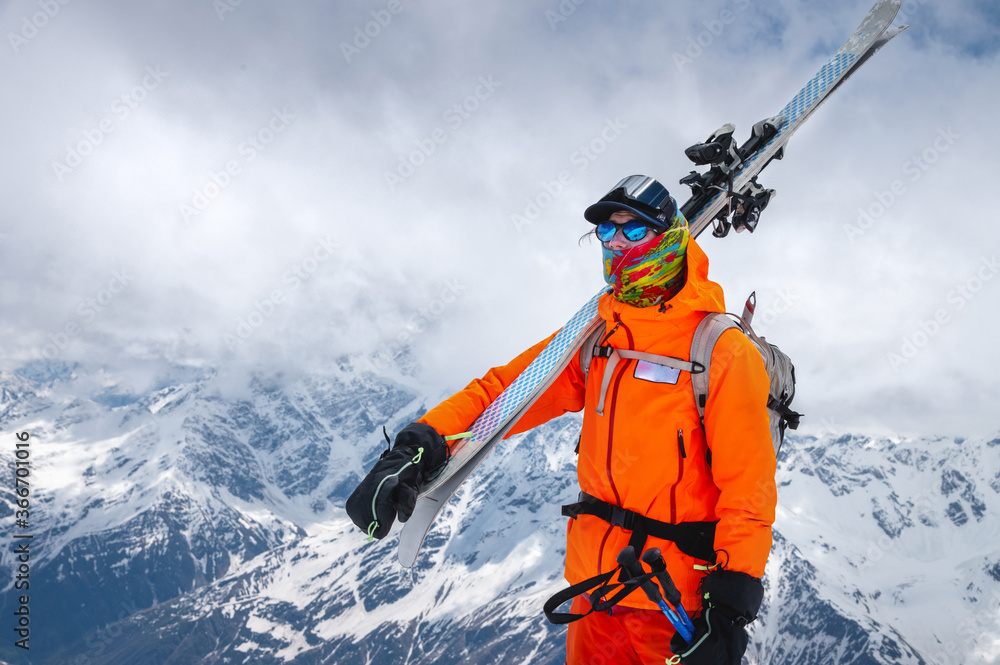 Portrait of an athlete skier with skis on his shoulder and a backpack on his back. Climbing the snow-covered mountains with ski tour skis and backcountry. Portrait of an athlete skier with skis on his shoulder and a backpack on his back. Climbing the snow-covered mountains with ski tour skis and backcountry.