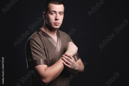 Studio portrait in a low key man professional physiotherapist confident and strong. The concept of a courageous therapist and massage therapist