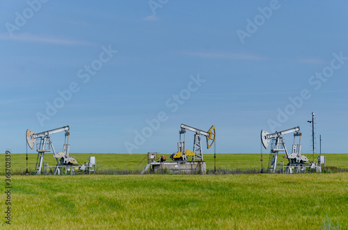 Rocking chair for oil production in a green field on a sunny day against a blue sky background.Extracts oil.
