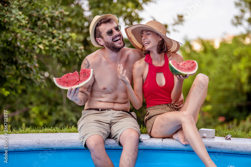 Lovely couple eating watermelons by poolside. © ivanko80