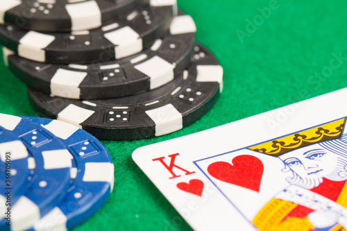 King Playing Cards and Blue and Black Casino Poker Chips. Pattern Isolated on Green Background Table.