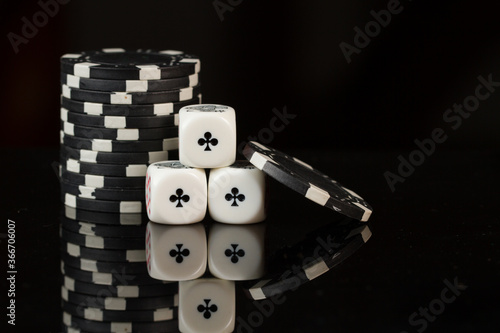 Casino playing poker black chips and three aces dice isolated on black background.