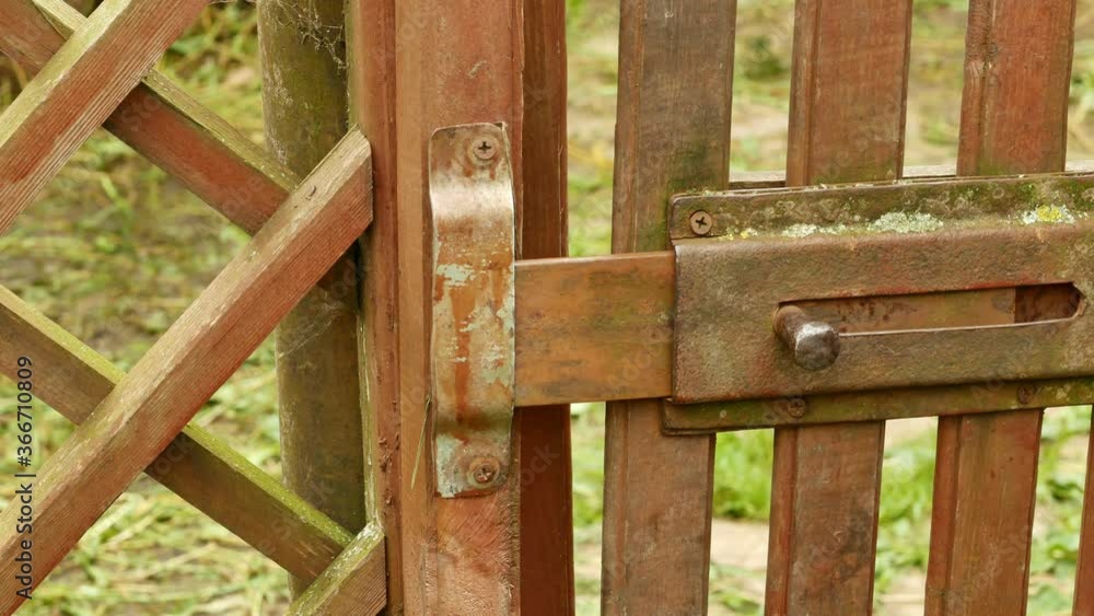Hand closes the gate on the bolt. An old fence. Hand closes the gate on the bolt. An old fence.