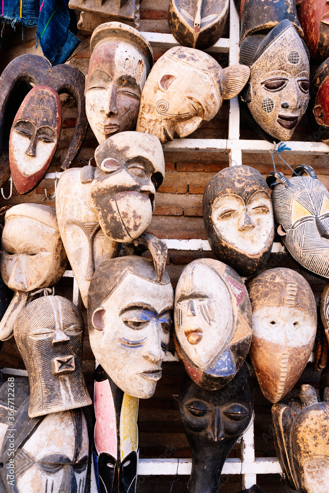 Vertical photo of some wooden masks hanging in a shop in a market