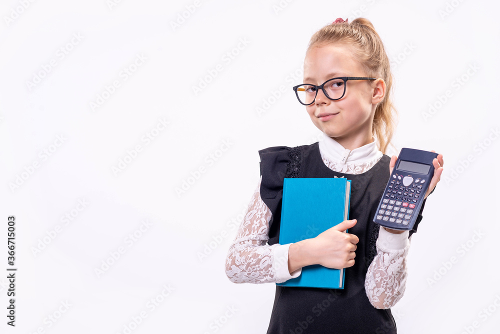 Little schoolgirl in glasses stands on a white background and holds a book and a calculator. Little schoolgirl in glasses stands on a white background and holds a book and a calculator.