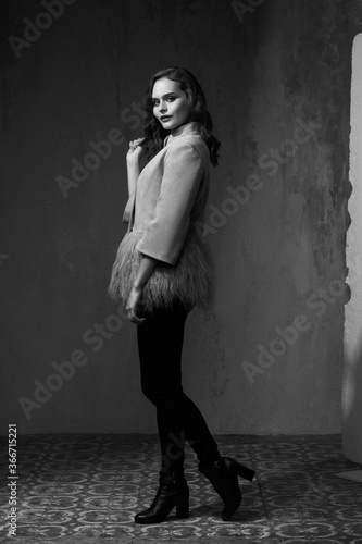 Fashion female model in coat against gray wall