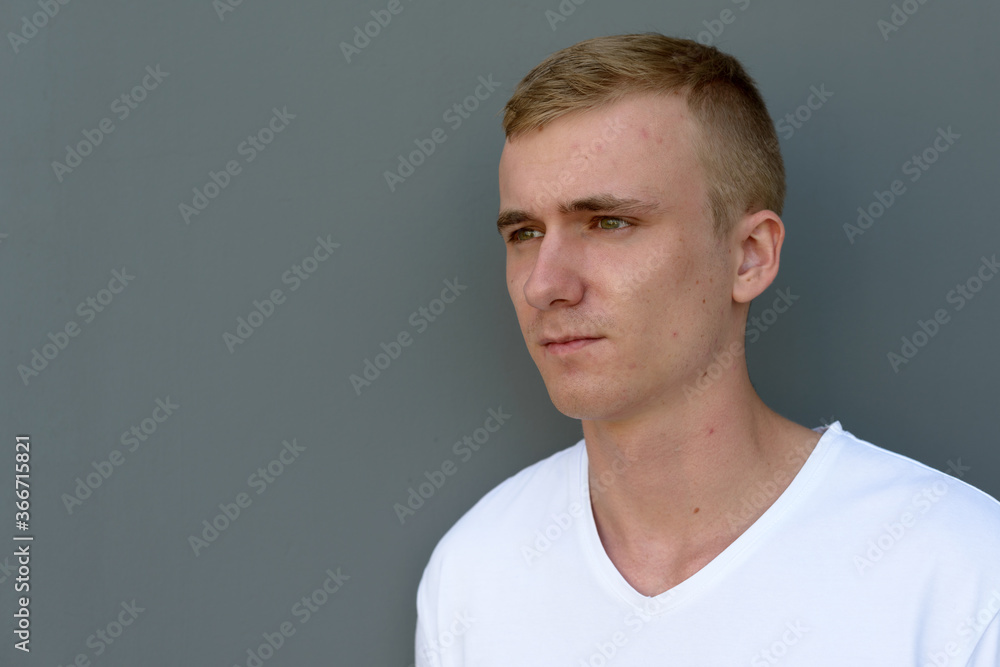 Portrait of young blond man against concrete wall outdoors Portrait of young blond man against concrete wall outdoors