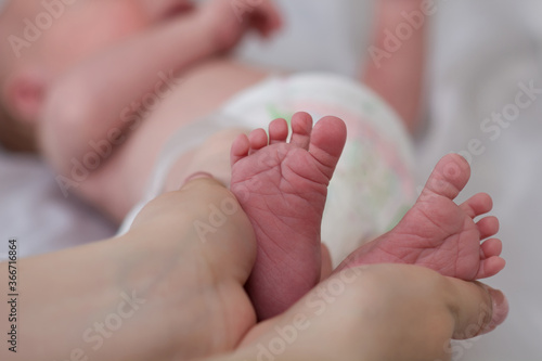 The parent gently holds the little feet of the newborn baby in his hands. Mom and Child. A beautiful conceptual image of motherhood. Happy family concept. Copyspace
