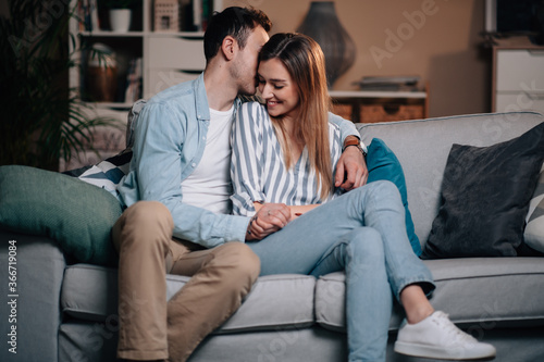 Portrait of a young couple in casual clothes on the couch in hugging each other